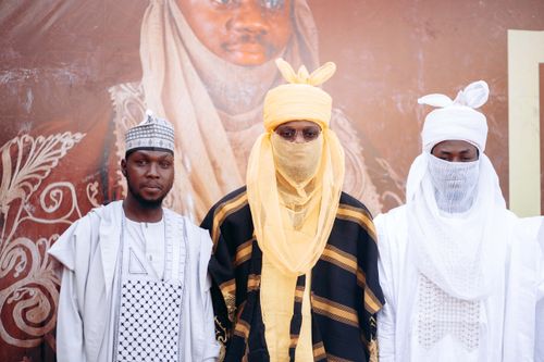 Free Three men in traditional Nigerian attire stand in front of a decorative background, showcasing cultural fashion. Stock Photo