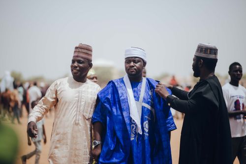 Free A lively gathering of men in traditional Nigerian attire enjoying a day outdoors. Stock Photo
