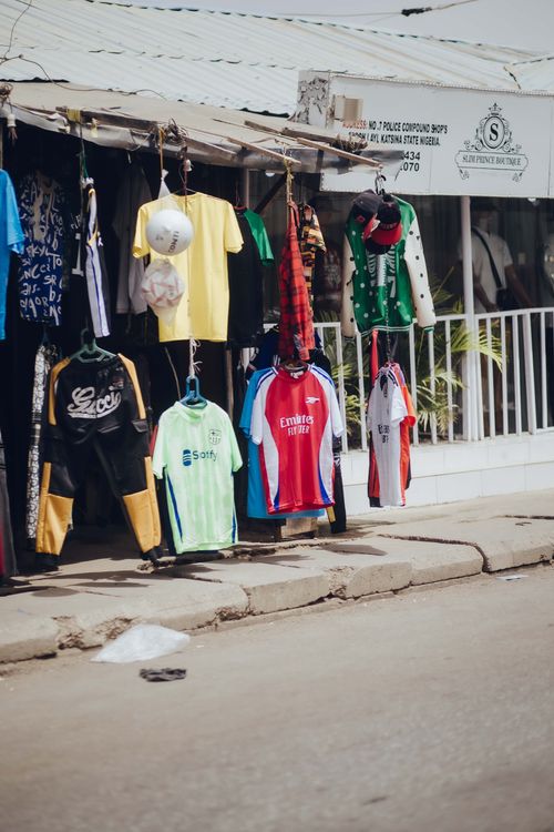 Free Street vendor with various colorful clothes hanging in a Nigerian market. Stock Photo