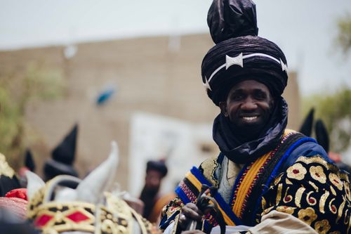 Free Smiling man in colorful traditional Nigerian attire on horseback during a cultural festival. Stock Photo