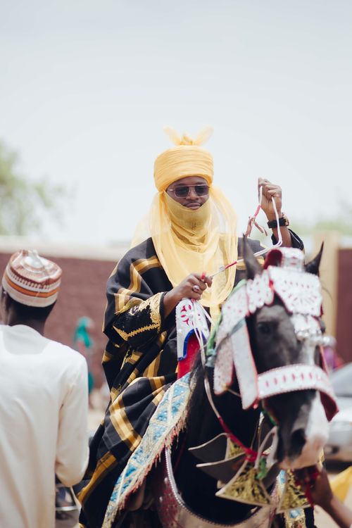 Free A traditional Nigerian rider in colorful attire and sunglasses participates in a cultural festival. Stock Photo