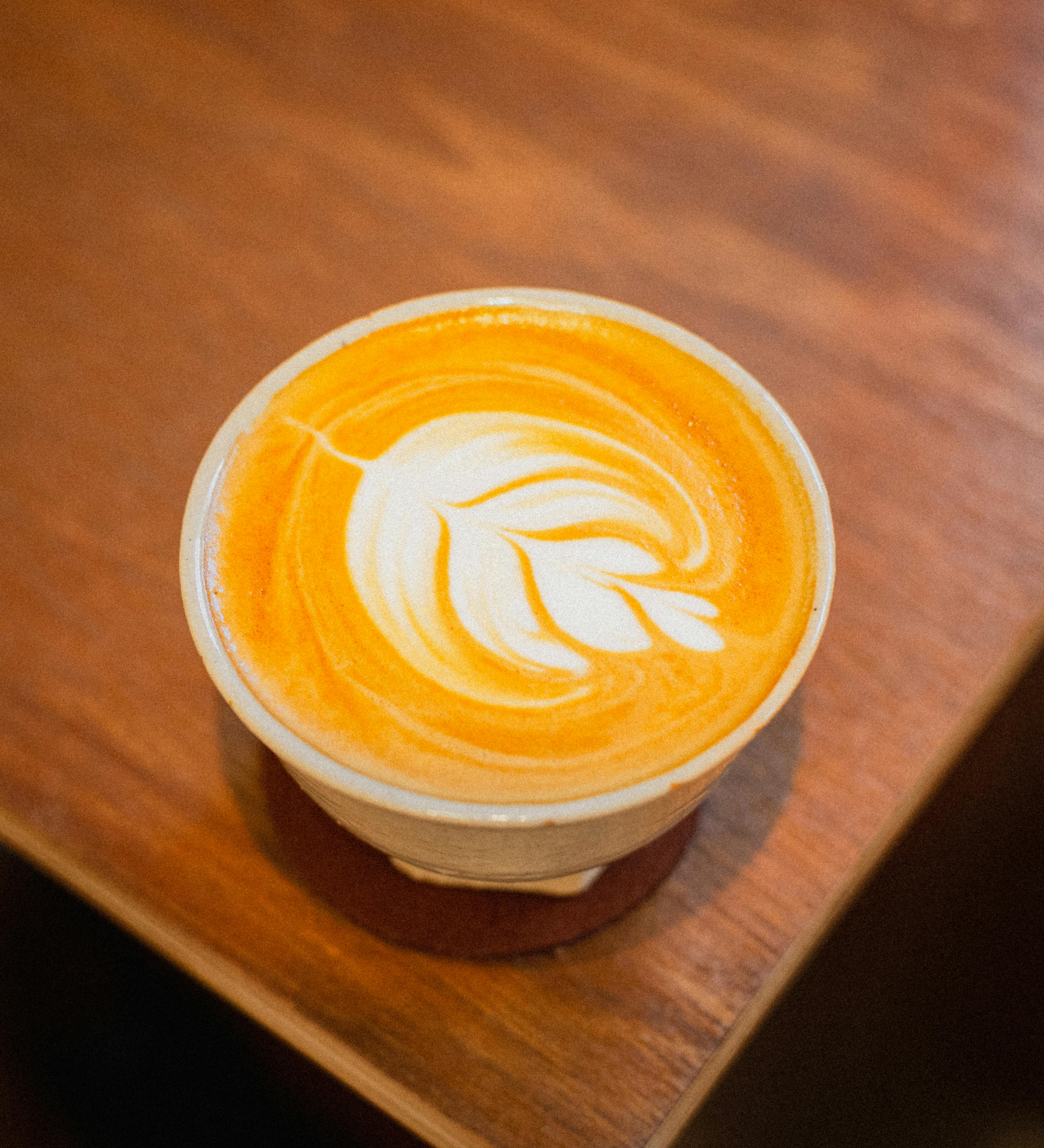Top view of a latte with leaf art on a wooden table in a cozy Tokyo cafe.