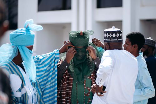 Free Men in traditional Nigerian attire participate in a cultural ceremony outdoors. Stock Photo
