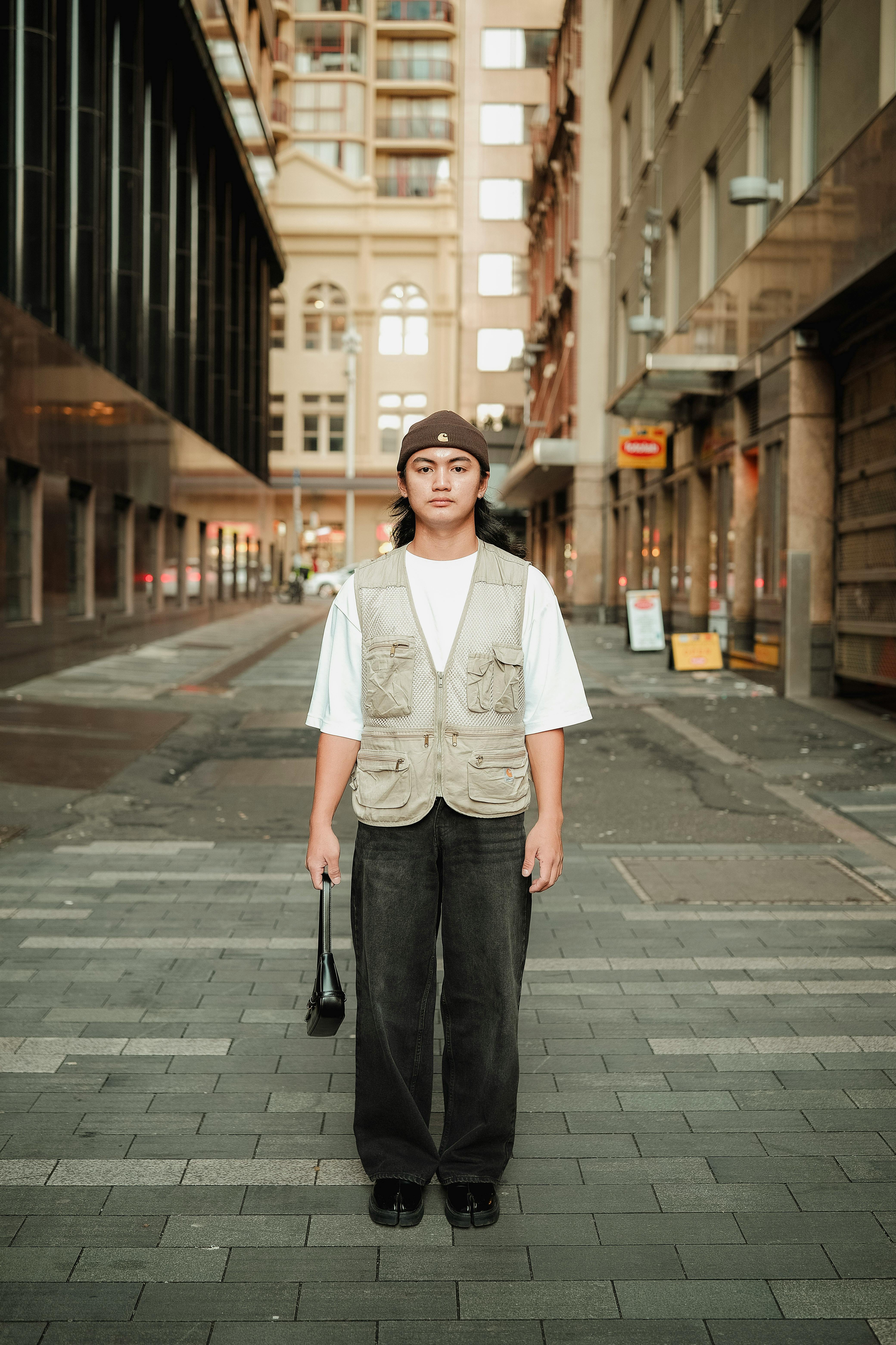 Stylish young adult posing confidently in a modern urban street setting.