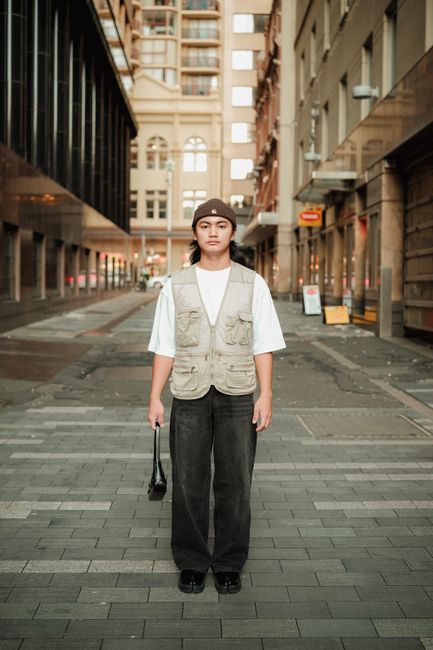 Stylish young adult posing confidently in a modern urban street setting.