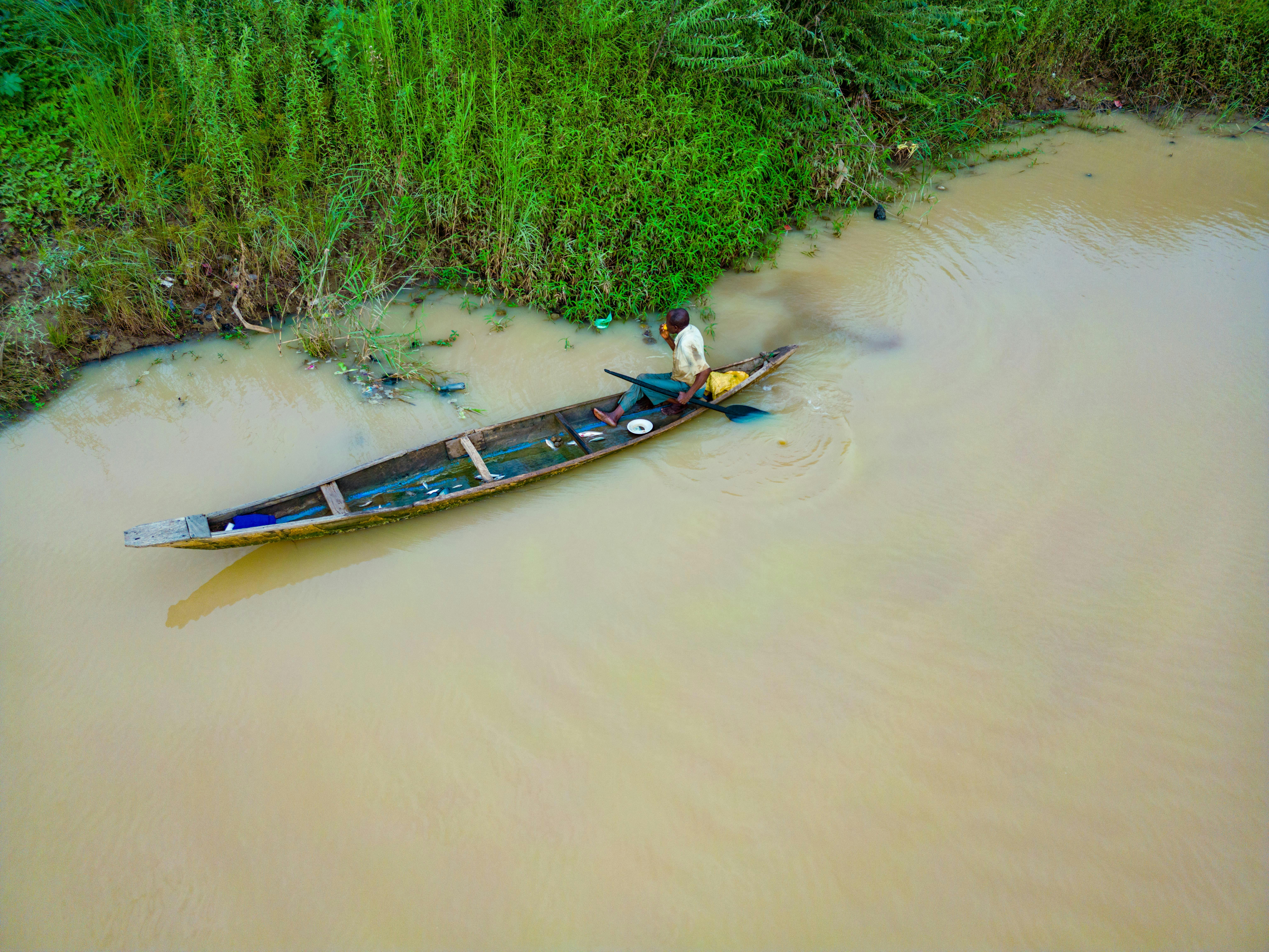 A fisherman paddles a wooden canoe on the calm waters of the Kaduna River in Nigeria.