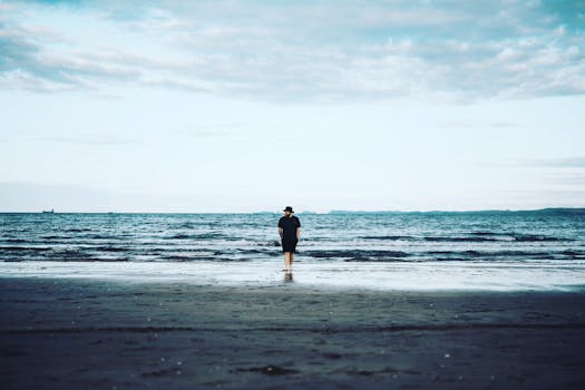 Person walking along a peaceful beach, embracing solitude and nature.