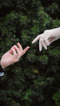 Elegant wedding scene capturing gloved hands reaching towards each other outdoors.