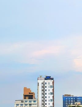 High-rise buildings against a cloudy sky, depicting urban architecture and open space.