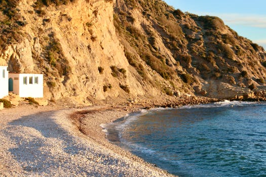 Captivating view of a pebble beach and rocky cliffs at Portixol, Javea, Spain during sunrise.