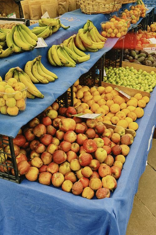 Free Colorful display of fresh fruits including apples, bananas, and peaches at a farmers market. Stock Photo