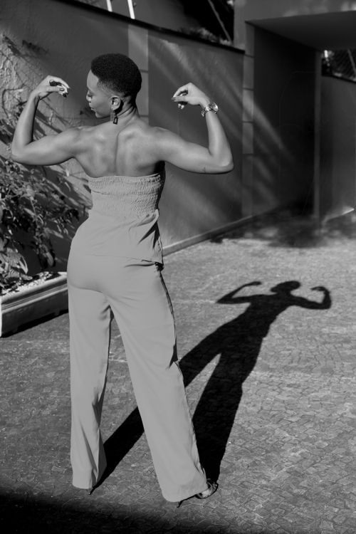 Free Confident woman flexing muscles outdoors with shadow reflection. Stock Photo