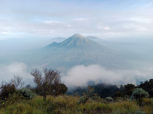Free Scenic view of a majestic mountain surrounded by mist and clouds, capturing the serenity of nature. Stock Photo