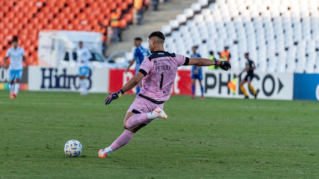 Dynamic shot of a soccer goalkeeper kicking during an intense football match.