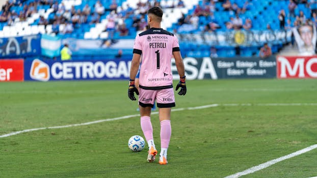 Goalkeeper in action during a football game on a sunny day outdoors.