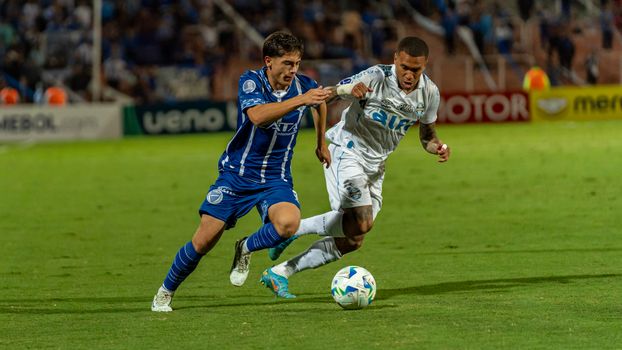 Two football players competing intensely during a soccer match on a field.