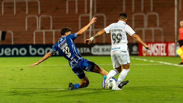 Intense moment as two soccer players clash in a tackle on the field during a competitive match.