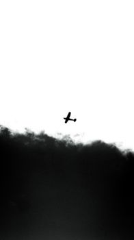 A striking black and white image showing a plane silhouette against a dramatic cloudy sky.
