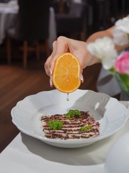Close-up of citrus being drizzled on a gourmet dish, indoors.