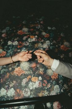A close-up of a couple exchanging wedding rings against a floral background, symbolizing eternal love.