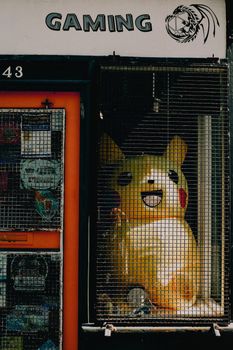 A large Pikachu figure is displayed behind a cage in a gaming store window.