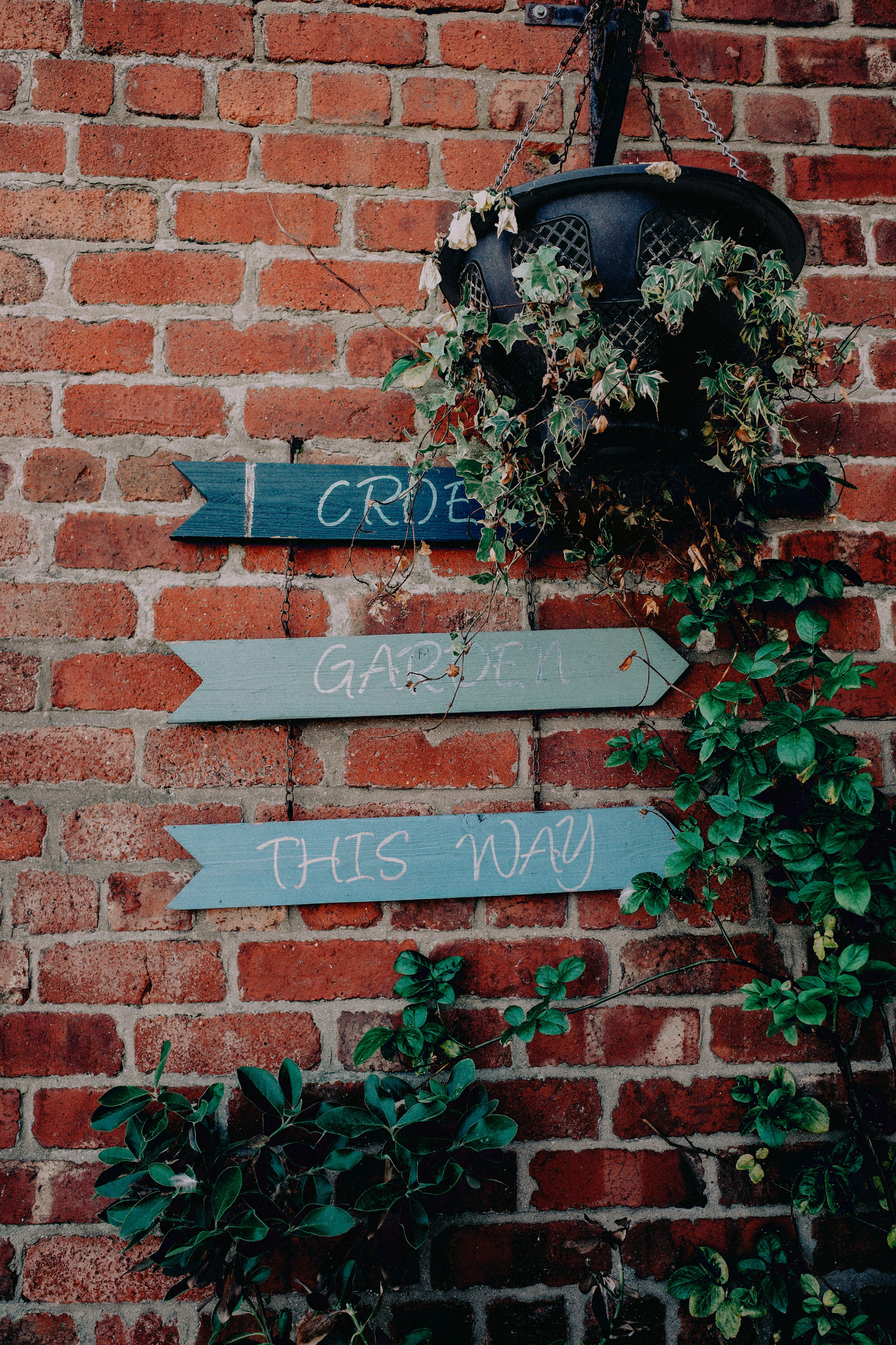 Rustic Garden Sign on Brick Wall Outdoors · Free Stock Photo