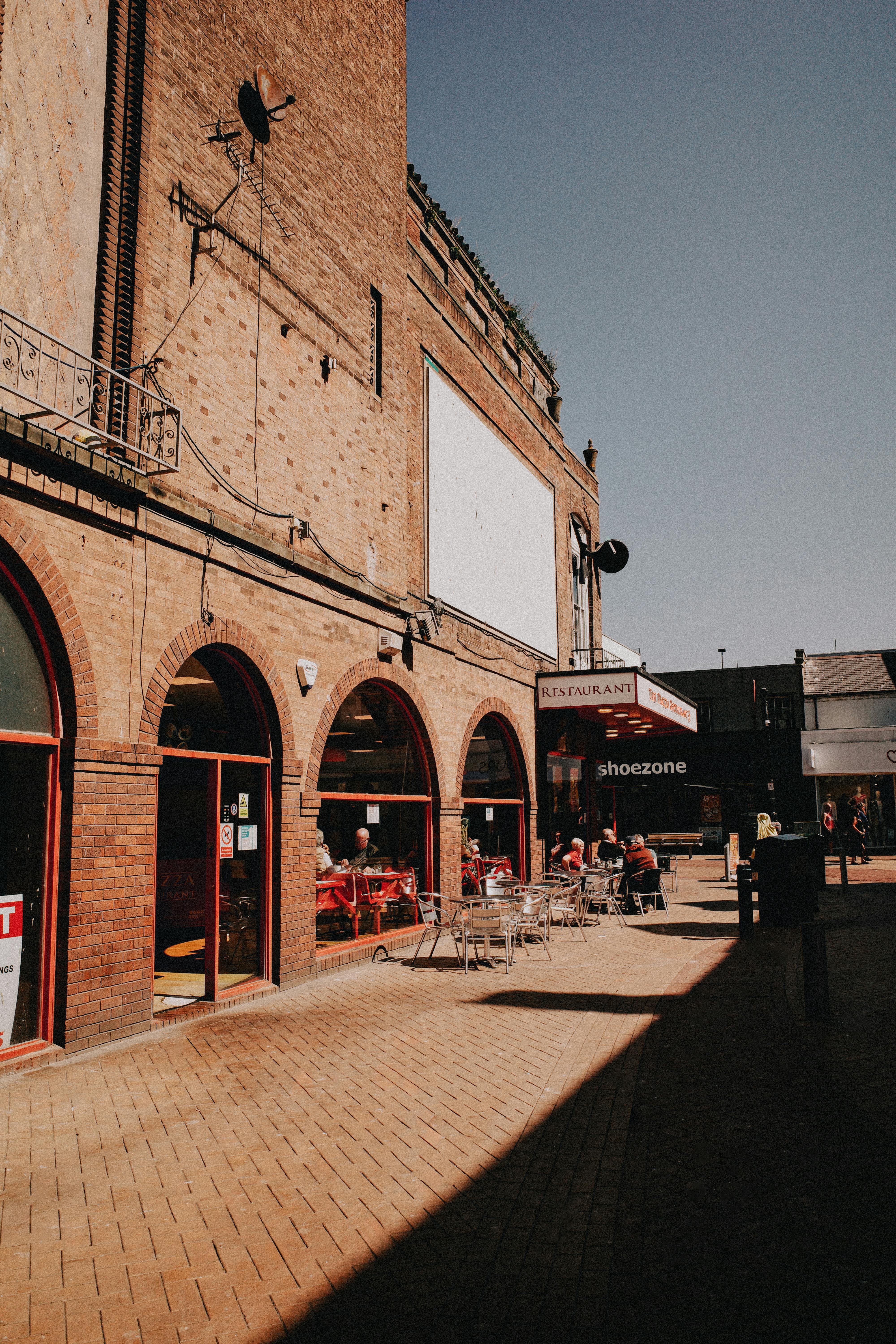 A bustling urban street scene with outdoor café seating on a sunny day.