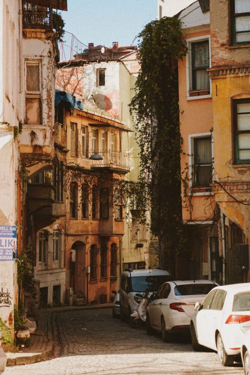Free Scenic old city street with vintage architecture and ivy-covered facades under a clear blue sky. Stock Photo