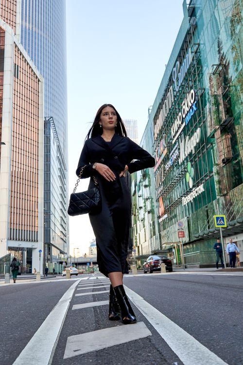 Free Confident woman in black walks through modern cityscape skyscrapers. Stock Photo