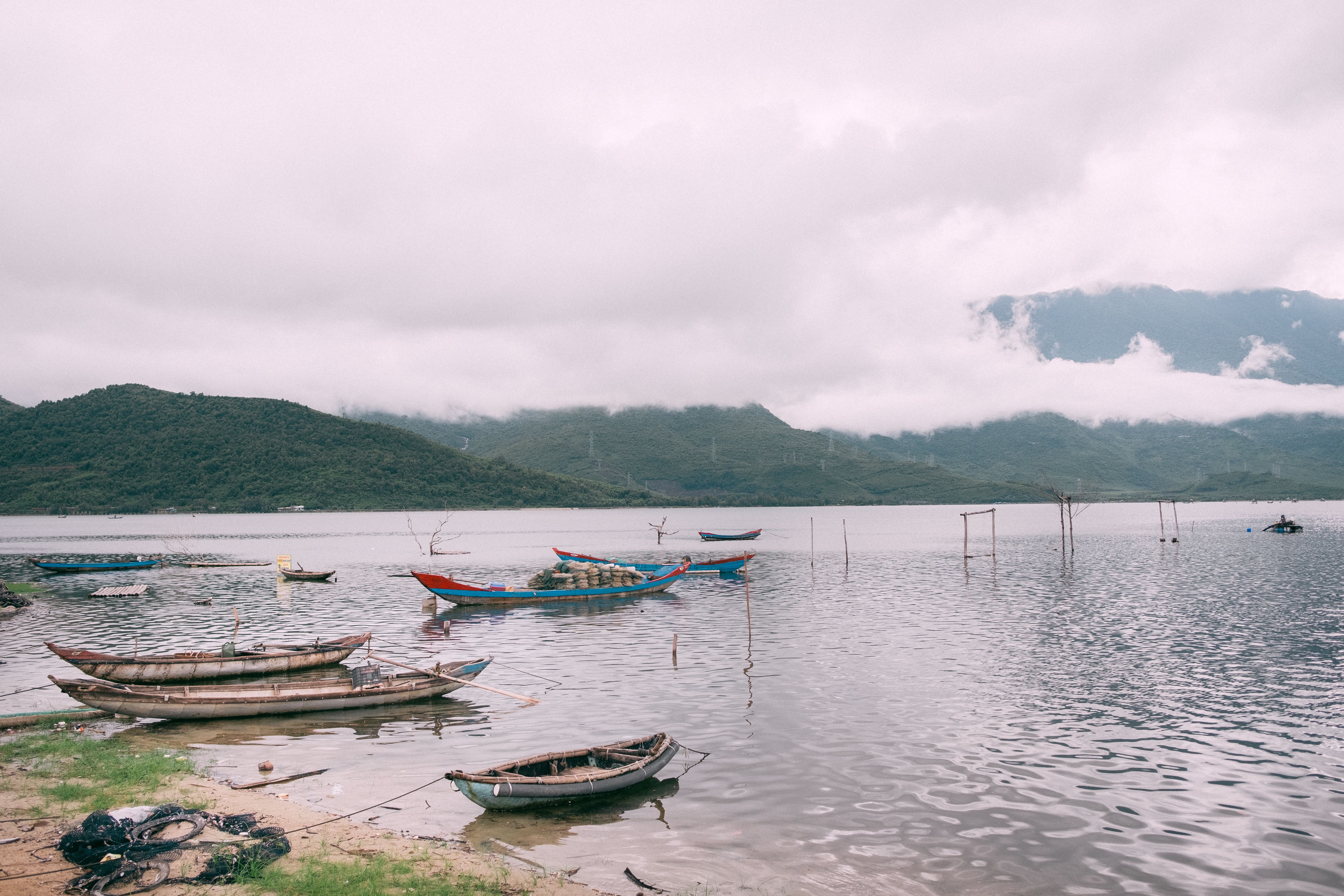 Tranquil Lake with Wooden Boats and Misty Mountains · Free Stock Photo