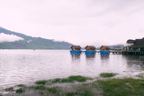 Free Three floating cabins on a serene lake with mountain backdrop, ideal for peaceful retreats. Stock Photo