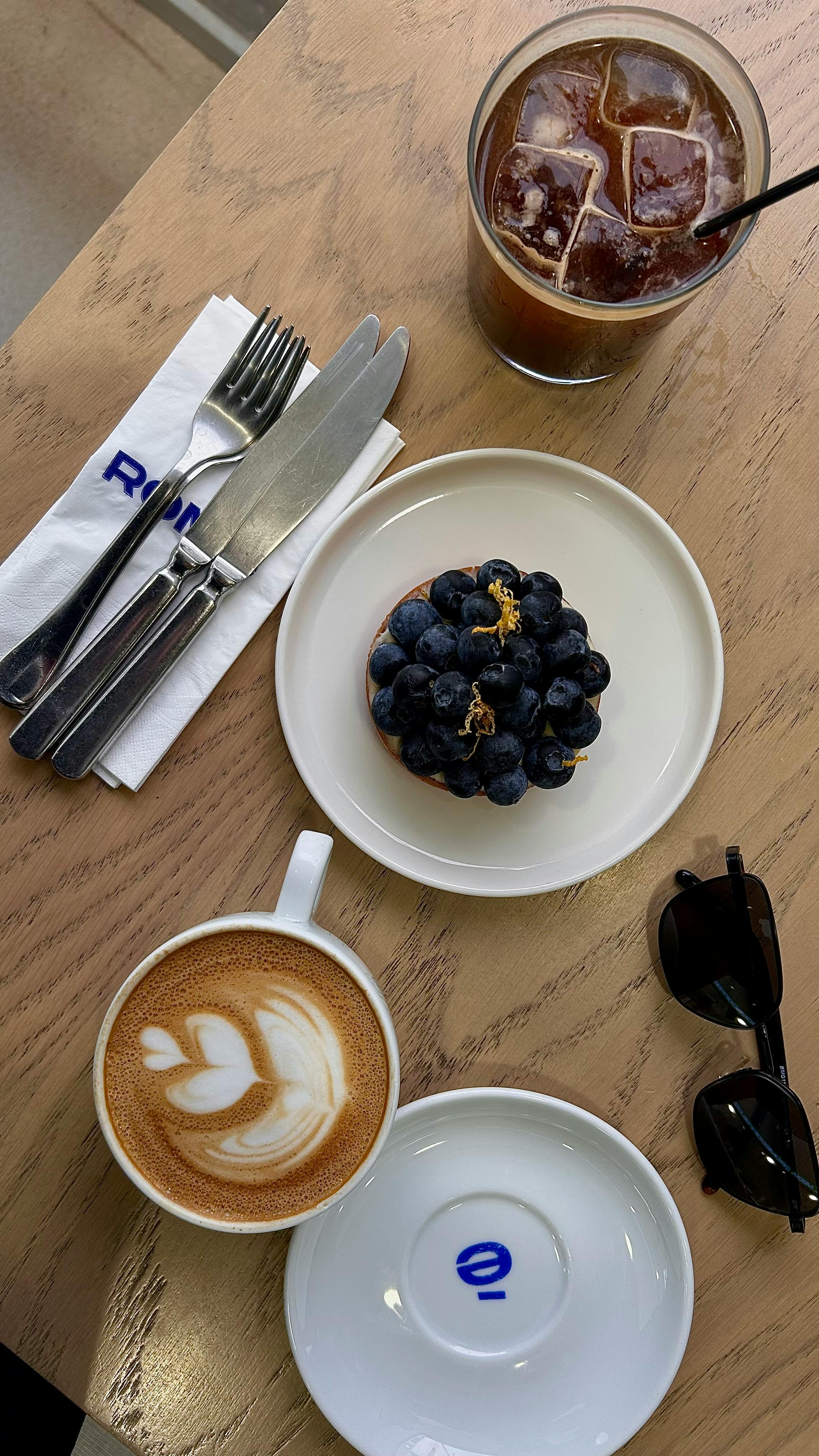 A delightful café scene featuring a blueberry tart, latte, and iced coffee.