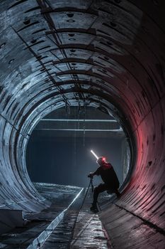 A photographer capturing a dramatic shot inside a large industrial tunnel.