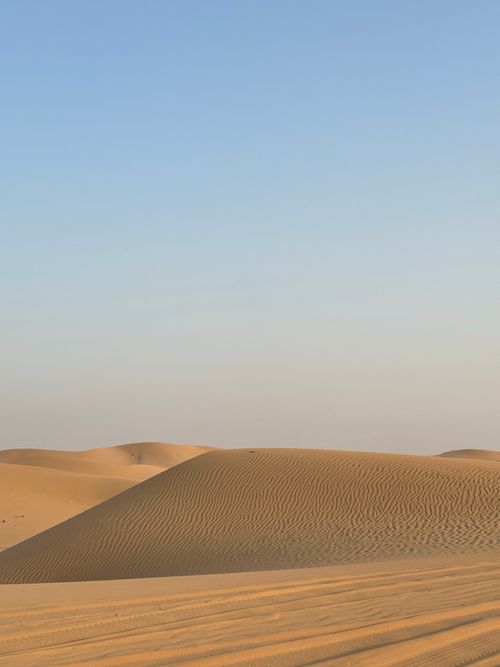 Free Expansive desert landscape with golden sand dunes and clear blue sky, serene and untouched. Stock Photo
