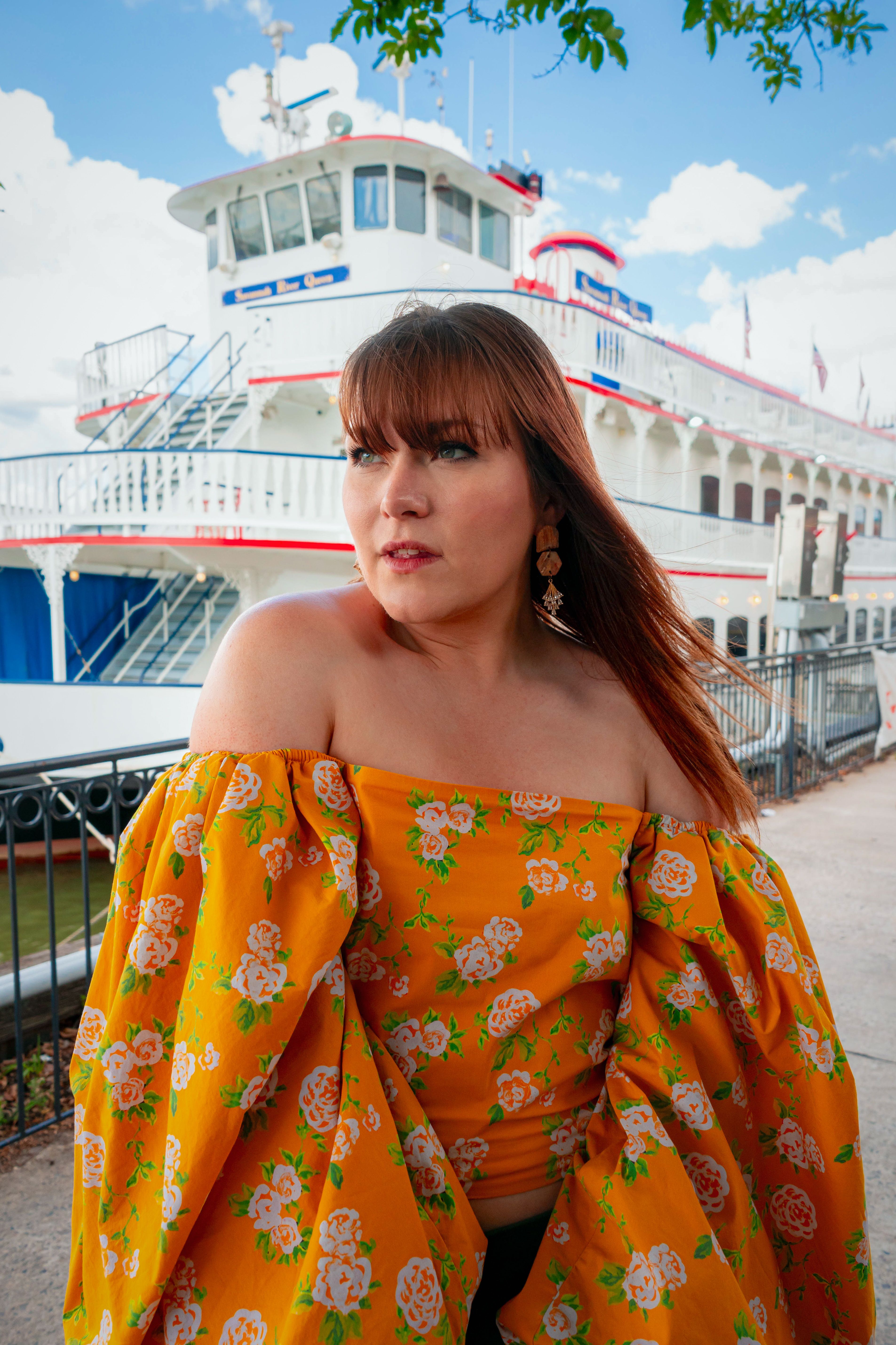 Vibrant summer fashion portrait with yellow floral top by a boat in Savannah, Georgia.
