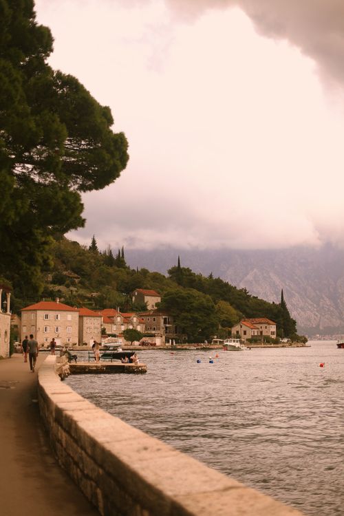 Free Charming seaside village in Montenegro with stone buildings and scenic mountain backdrop. Stock Photo