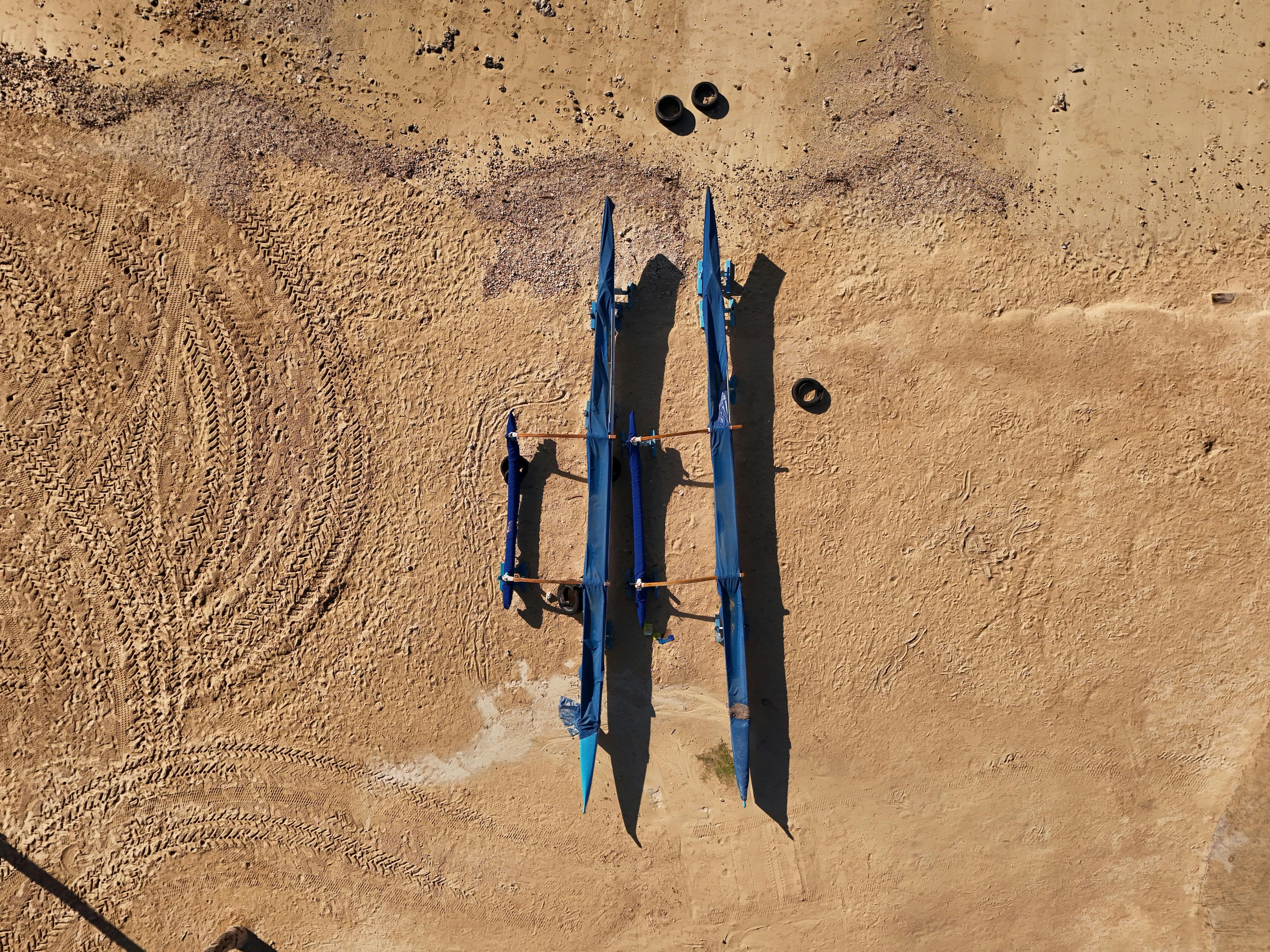 Aerial shot of three blue canoes on a sandy beach in Honolulu, Hawaii, during the day.