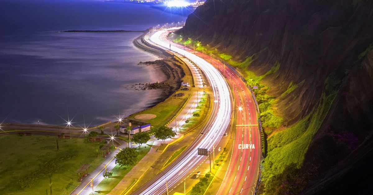 A vibrant aerial shot of Lima's coastline at night, showcasing urban lights against the ocean.