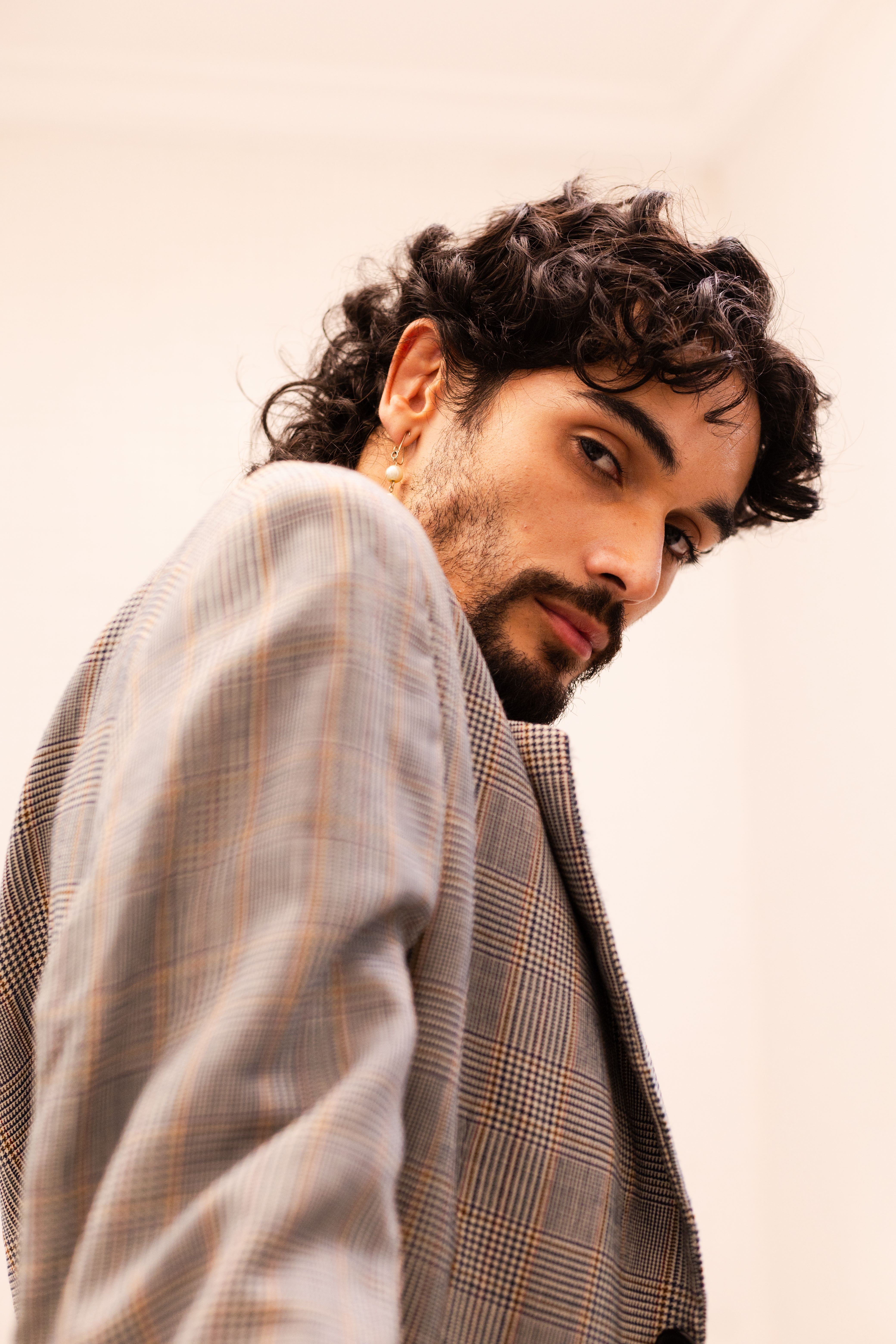 Elegant portrait of a man in a plaid blazer with a thoughtful expression, shot indoors in São Paulo, Brazil.