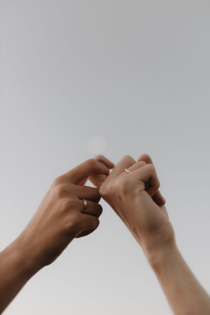 Two hands holding each other with love and affection against a clear sky.