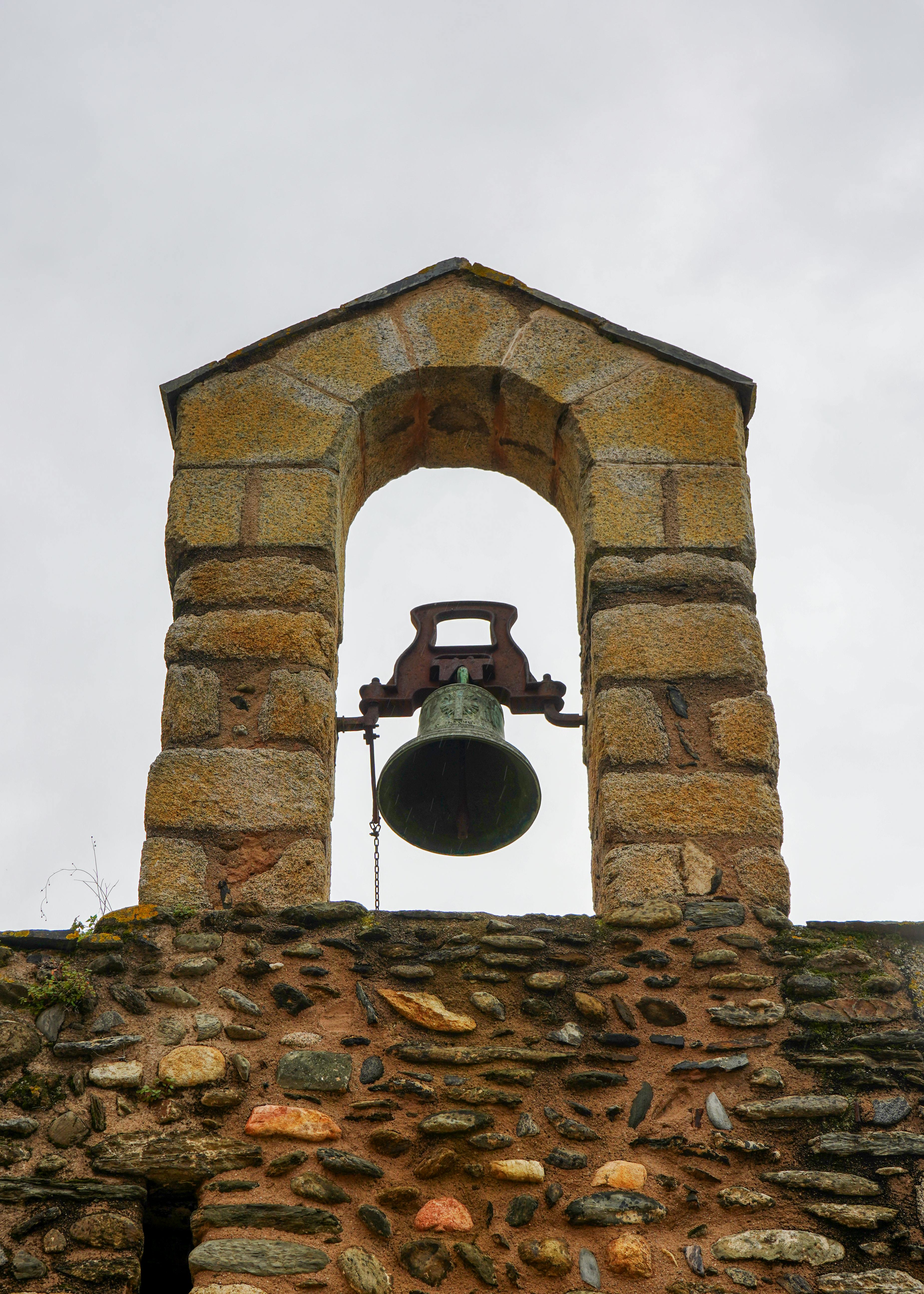 Gratis Un campanario antiguo de piedra con aspecto desgastado sobre un fondo nublado. Foto de stock