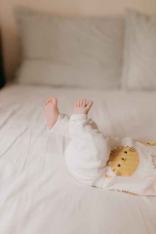 Free Close-up of baby feet in white pajamas on a comfy bed, creating a warm and cozy feel. Stock Photo