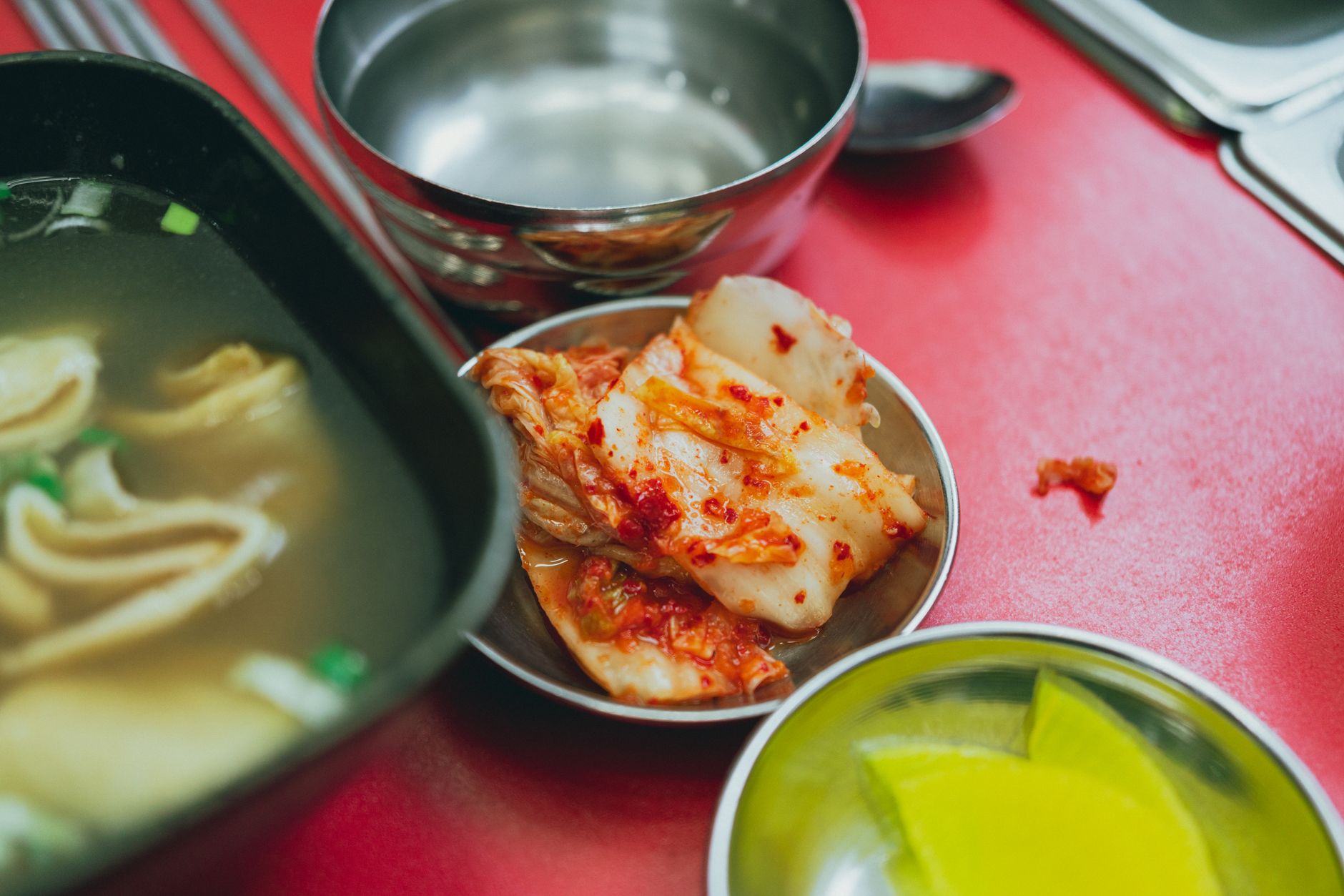Close-up of traditional Korean kimchi and soup served on a vibrant red table.