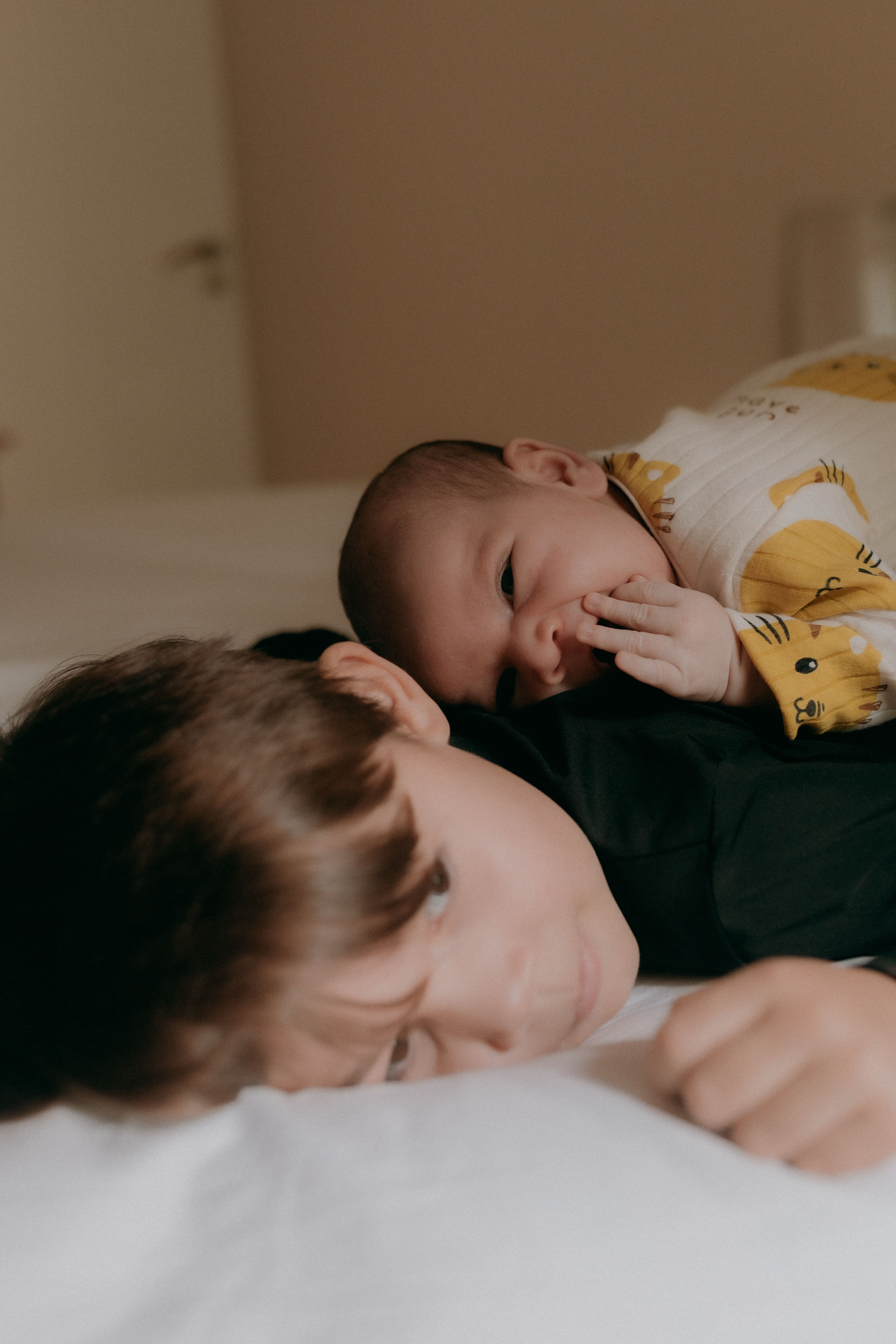 A loving moment between a baby and child siblings on a cozy indoor bed.