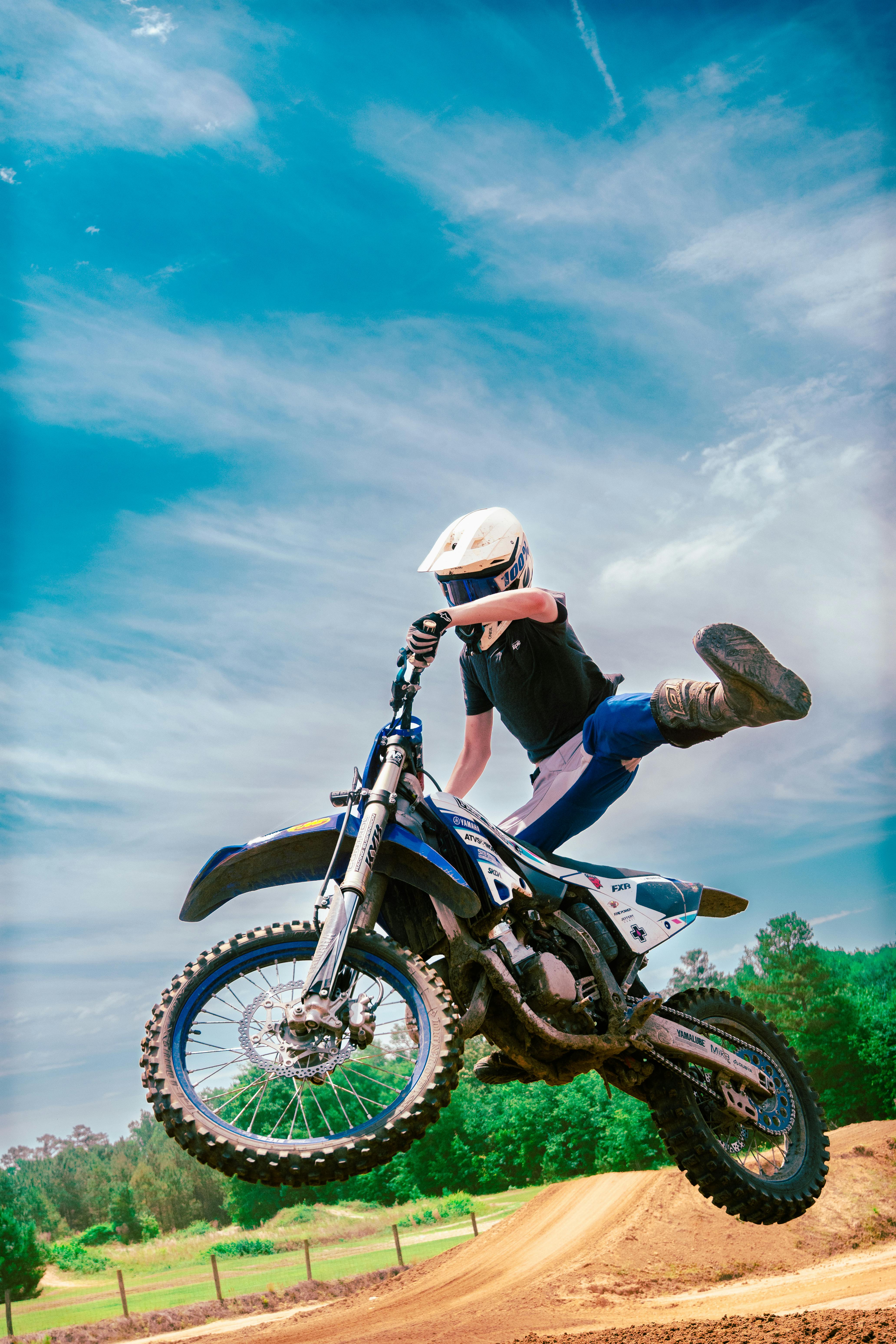 Action-packed motocross jump captured in mid-air on a sunny day.