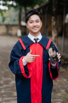 Young graduate in cap and gown celebrating via video call outdoors.