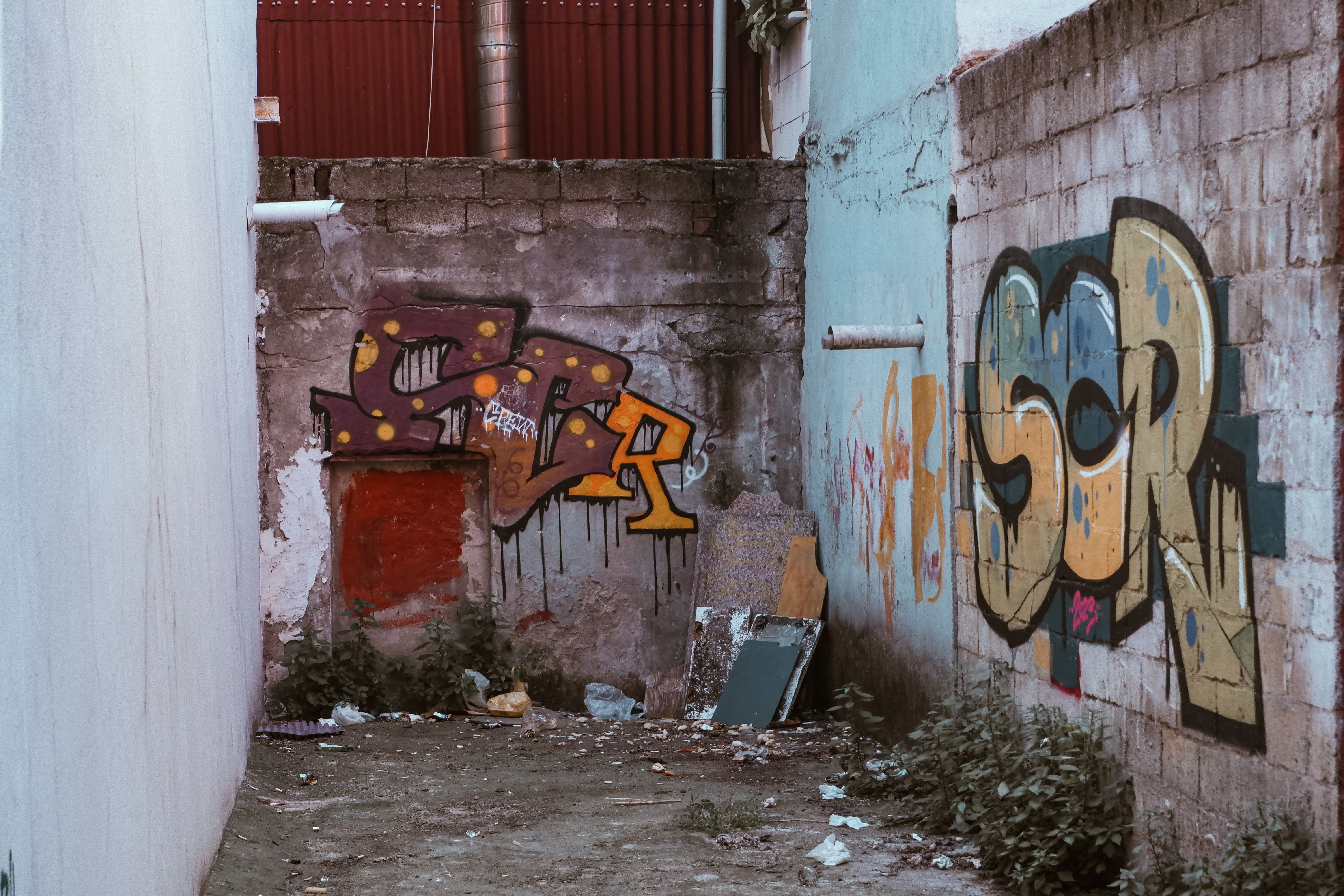 Grungy urban alley adorned with vibrant graffiti art on weathered walls, capturing street culture.