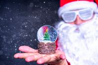 一幅圣诞老人手持雪球和圣诞树的节日图像