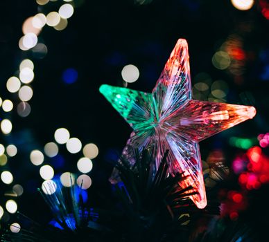 Close-up of a star ornament with vibrant bokeh Christmas lights enhancing the festive mood.