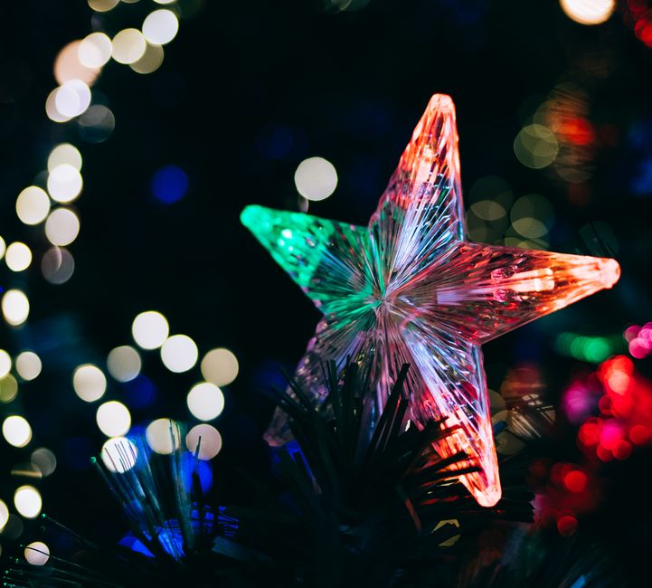 Close-up of a star ornament with vibrant bokeh Christmas lights enhancing the festive mood.